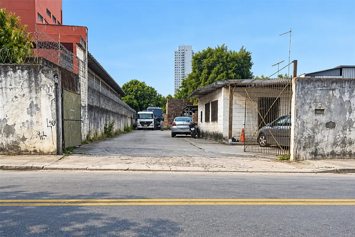 Entrada da Auto Elétrico Nagasse e Yamasaki vista da rua, com portão aberto e caminhões no pátio ao fundo
